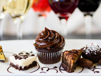 A close up of chocolates with glasses of wine in the background