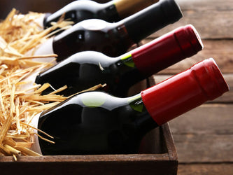 Unopened wine bottles laid out in a straw-filled box